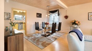 Ein modernes Wohnzimmer mit Essbereich, Holzboden und Blick zur Küche.