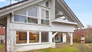 Ein zweistöckiges Haus mit großen Fenstern, einer Satellitenschüssel und einer sichtbaren Garage.