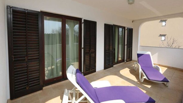 A balcony with two sun loungers and a sliding glass door.