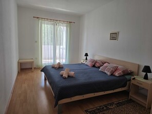 A bedroom with a bed, bedside tables, a nightstand, a window with curtains, and a small picture on the wall. - Apartment Tena (Silo - island Krk)