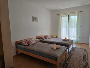 A room with two beds, a small table, and a window with curtains. - Apartment Tena (Silo - island Krk)
