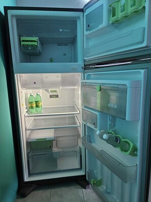 Ein offener Kühlschrank mit mehreren Regalen und Schubladen, der Flaschen und Behälter enthält.