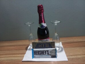 Eine Weinflasche, zwei Weingläser und eine Tafel Schokolade von Hershey auf einem Holztisch.