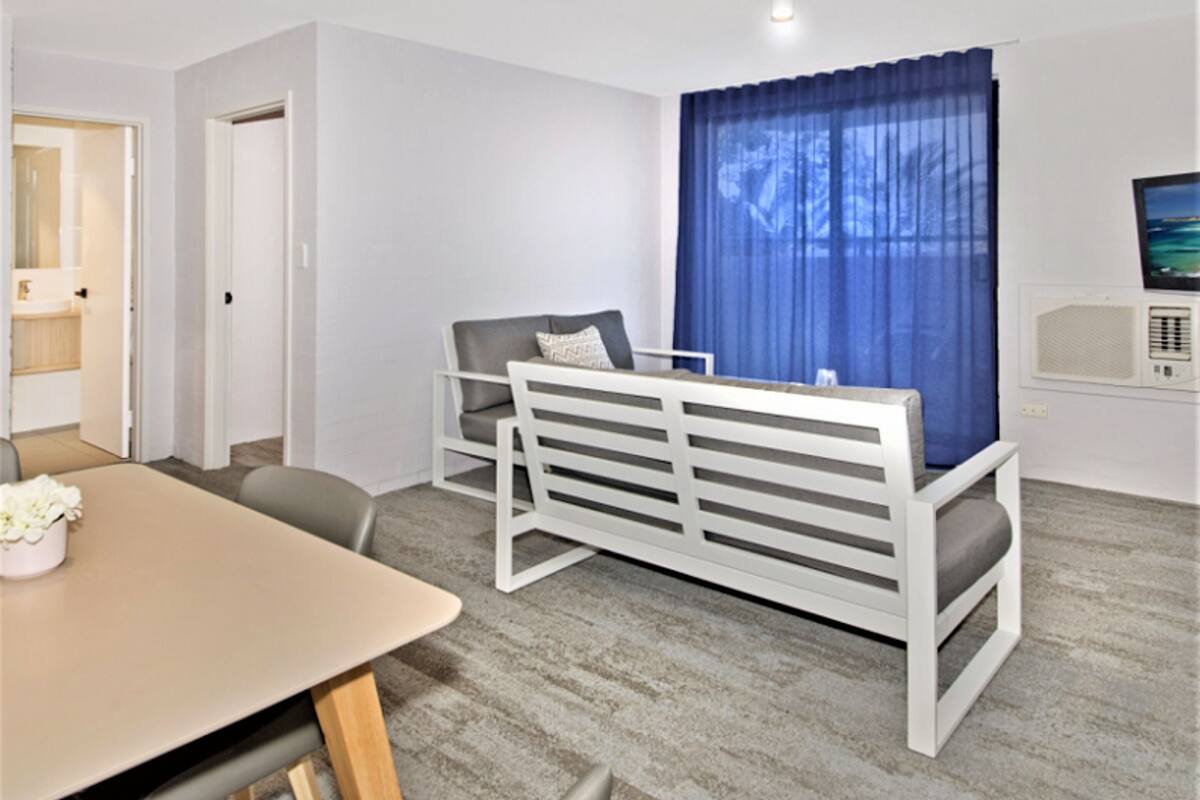 A modern room with a bed, a desk, and a television.