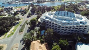 Un hôtel doté d’un toit circulaire original, entouré d’une zone côtière comprenant un port de plaisance et des immeubles résidentiels.