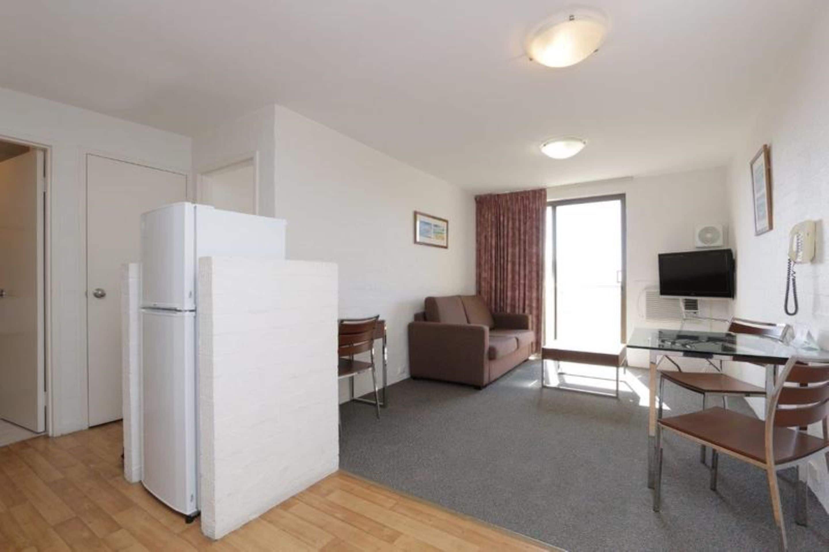 A compact living space with a kitchenette, a dining area, and a seating area with a sofa and chairs.