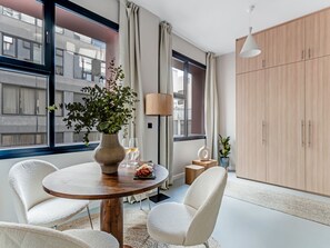 Enjoy a city view from the comfort of this stylish room, featuring a large window, a spacious wardrobe, and a cozy seating area.