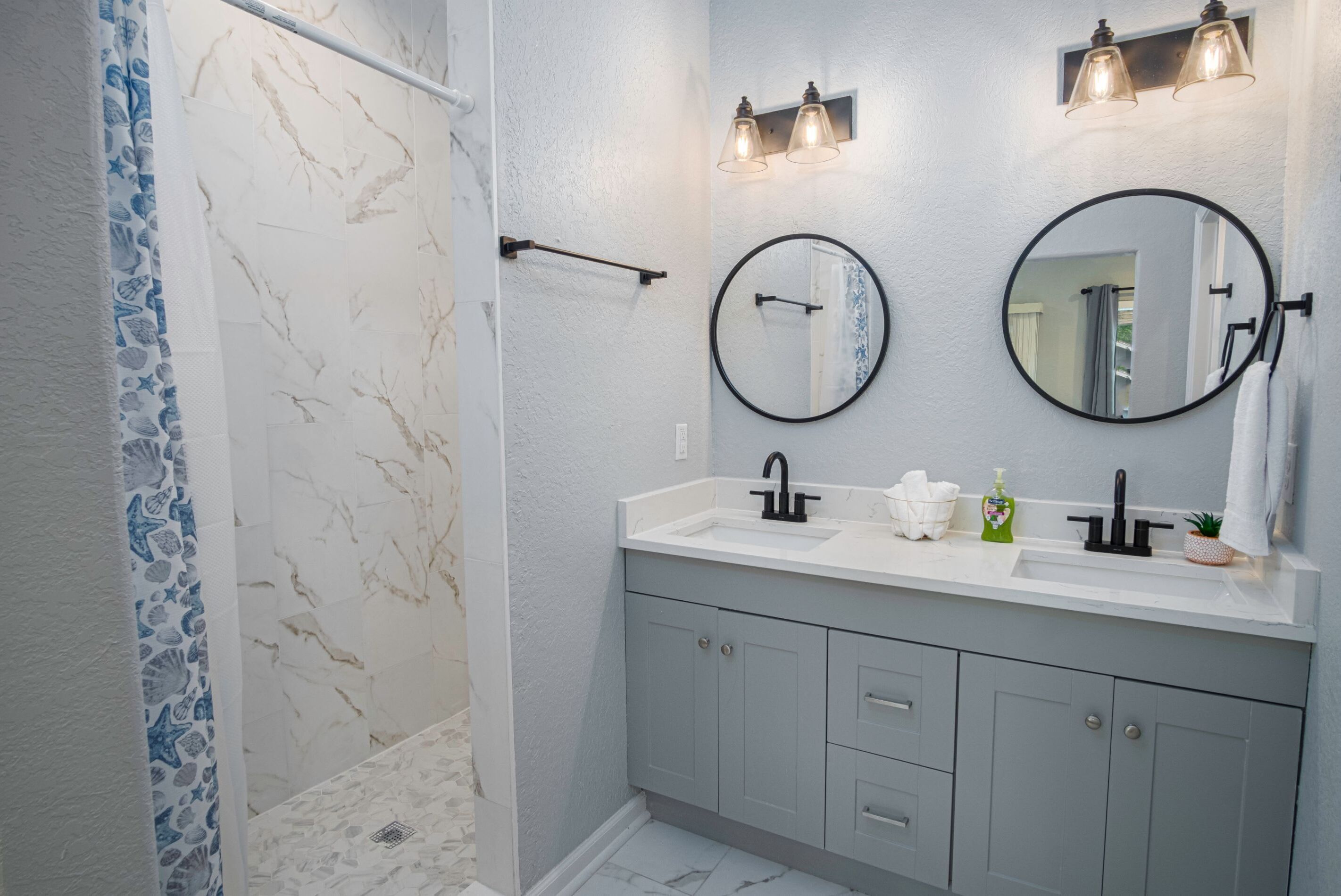 Une salle de bain avec une douche, deux lavabos et un miroir.