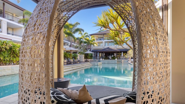 A wicker cabana with a view of a pool and a building in the background. - Luxe King Studio in Santai (Tweed)