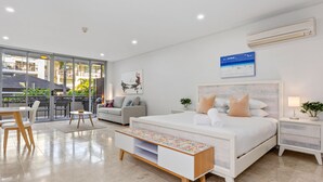 A modern bedroom with a large bed, a sofa, a dining table, and a balcony with outdoor seating. - Luxe King Studio in Santai (Tweed)
