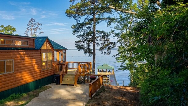 Una cabaña de madera con un porche y un mirador junto a un lago.