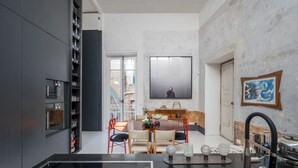 Una cocina moderna con comedor, que incluye un horno empotrado, un ventanal grande y un cuadro en la pared.