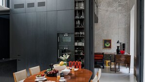 Un comedor moderno con una mesa de madera, sillas rojas y una estantería empotrada para vinos.