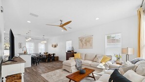 A spacious living area with a sofa, coffee table, and a dining table set. - Family Getaway•4BR•Games•Fire Pit•Easy Beach Access•Fenced Yard•Pet Friendly  (Panama City Beach)
