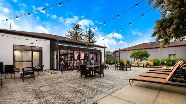 Un espace extérieur aménagé en terrasse, avec un coin salon couvert, une piscine et des chaises longues.
