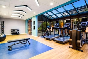 Ein Fitnessraum mit Laufbändern, einer Bank und Trainingsbällen.