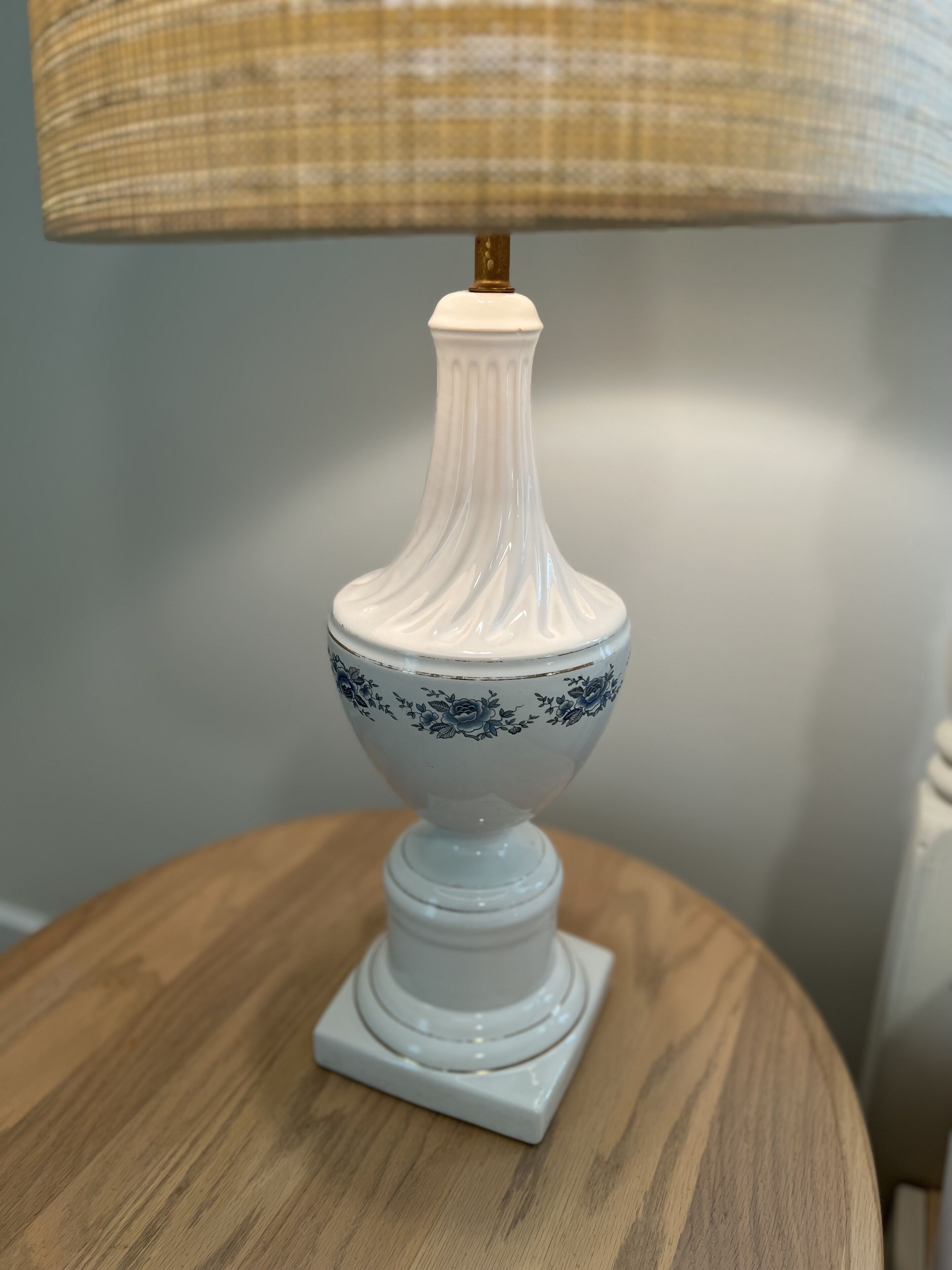 A white ceramic lamp with blue floral patterns on a wooden table.