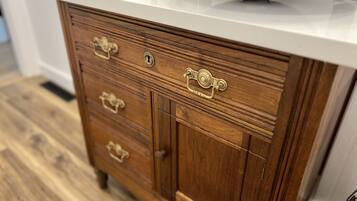 A wooden dresser with brass handles and a white countertop.