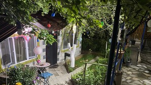 A garden patio with a table and chairs, surrounded by potted plants and flowers. - Mimihouse (Tbilisi)