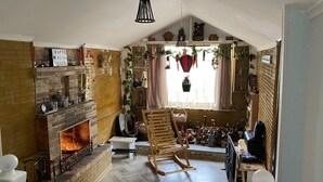 A cozy living room with a fireplace, wooden furniture, and decorative items. - Mimihouse (Tbilisi)