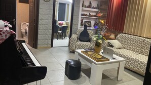 A living room with a piano, a sofa, a coffee table, and a dining area in the background. - Mimihouse (Tbilisi)