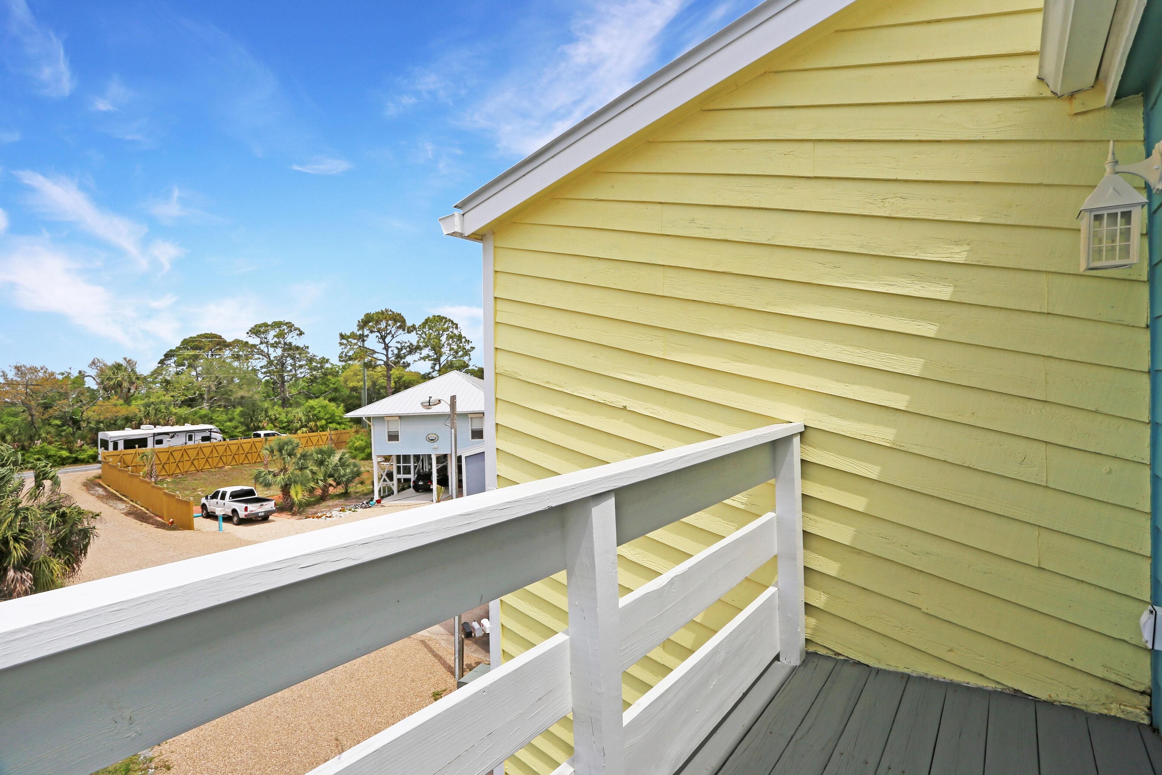 A yellow building with a white railing and a small white lantern.