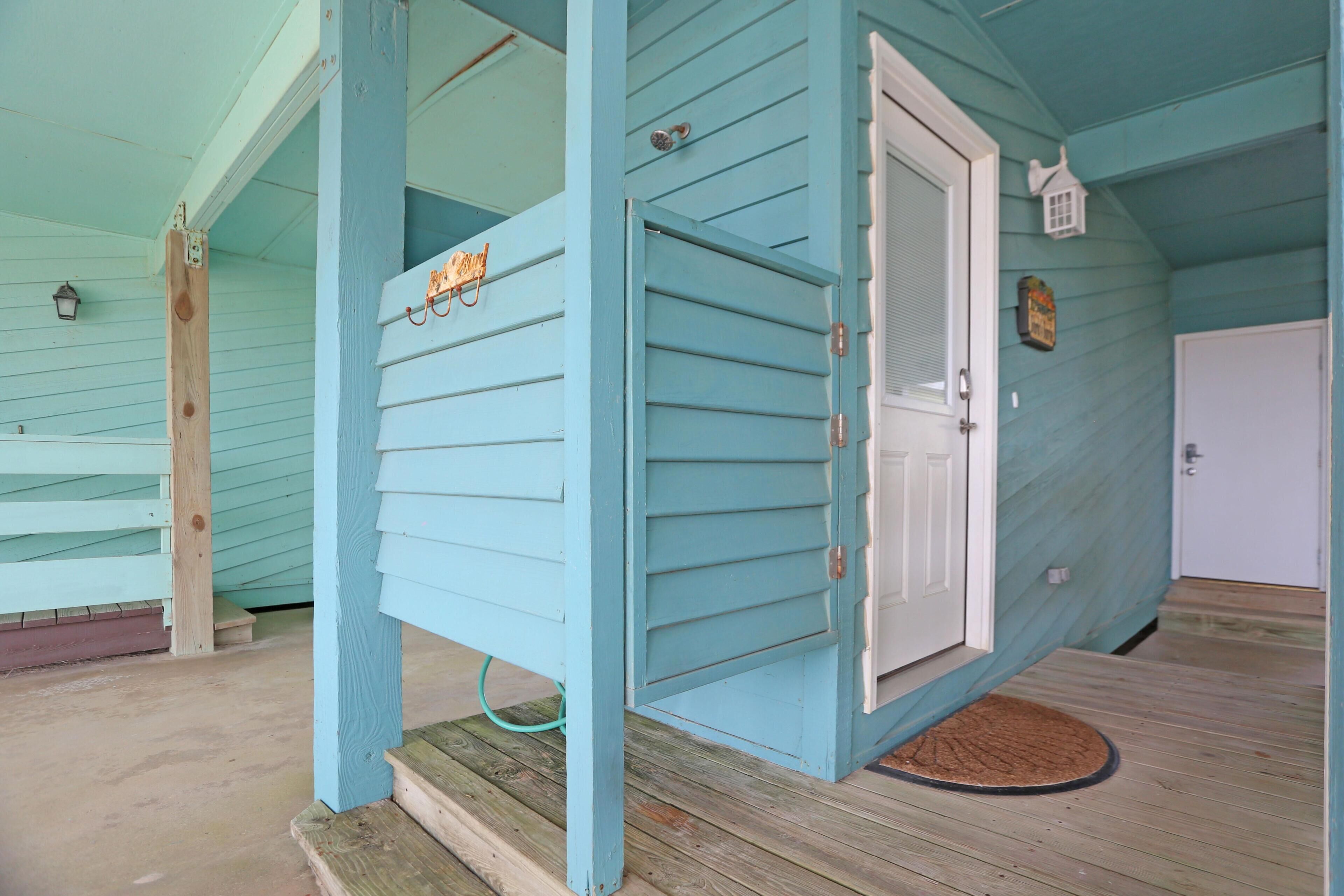 A light blue wooden house with a white door and a small porch.
