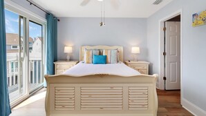 A bedroom with a large bed, two bedside tables, a ceiling fan, and a view of the outside. - Barrier Dunes 268 - 101 Cape Blessed (Port St. Joe)
