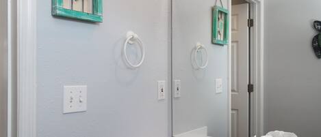 Un baño con un lavamanos blanco, un espejo y un sujetarobas en la pared.