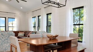 A spacious living area with a wooden dining table, comfortable seating, and large windows offering natural light. - Emerald Palms 3 (Port St. Joe)