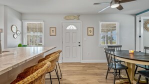 Una cocina moderna con una isla central, taburetes de bar y un comedor con mesa y sillas.