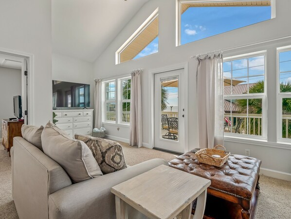 A spacious living room with a large window, a television, and a comfortable seating area.