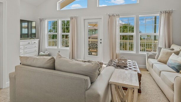 Un salón comedor amplio con techos altos, ventanas grandes y vistas al exterior.