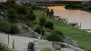 Vista panorámica de un lago con muelle, zonas verdes y un atardecer.