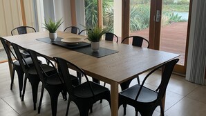 Un comedor con una mesa rectangular, sillas negras y dos plantas en macetas.