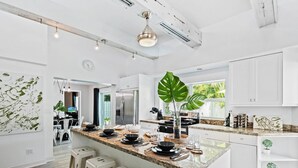 Uma cozinha moderna com ilha central, eletrodomésticos de aço inoxidável e uma janela grande que ilumina naturalmente o espaço.