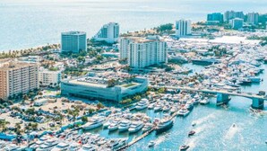 Uma marina com vários barcos atracados, rodeada por edifícios altos e uma ponte.