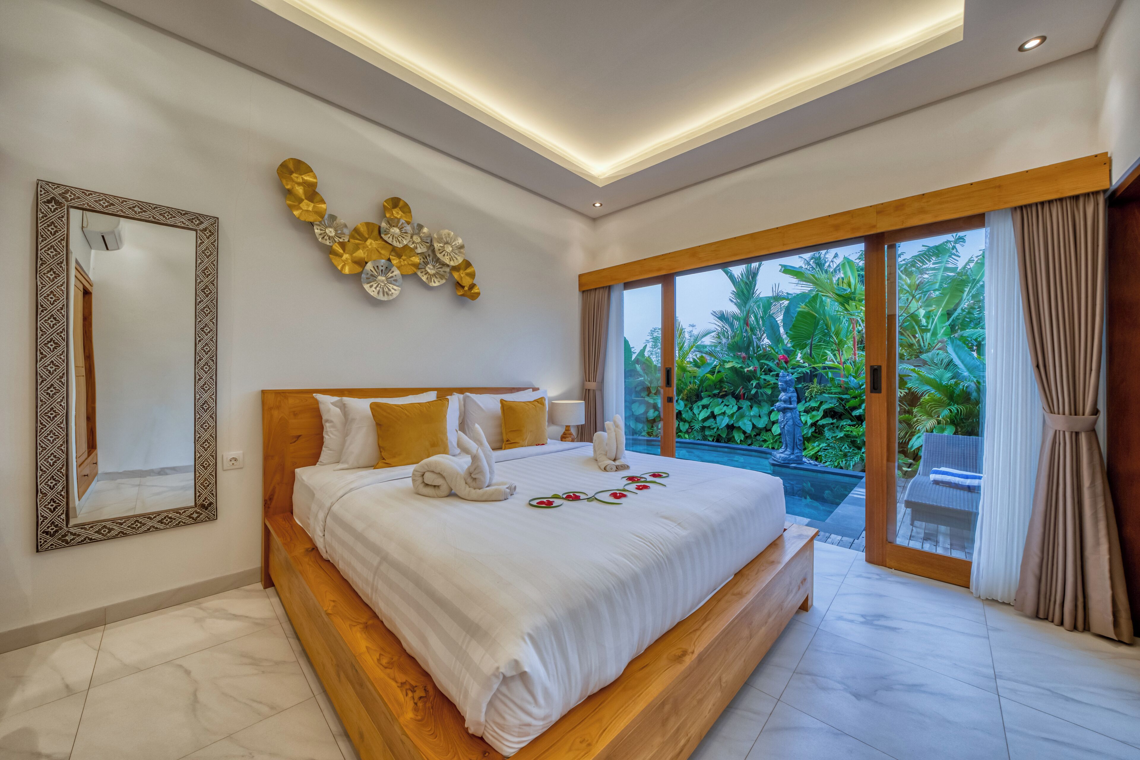 Un dormitorio amplio con una cama grande, un espejo y vistas a una piscina.