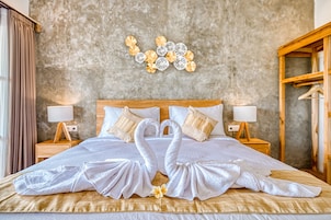 A hotel room with a large bed, two nightstands, a wooden wardrobe, and a decorative wall piece above the bed.