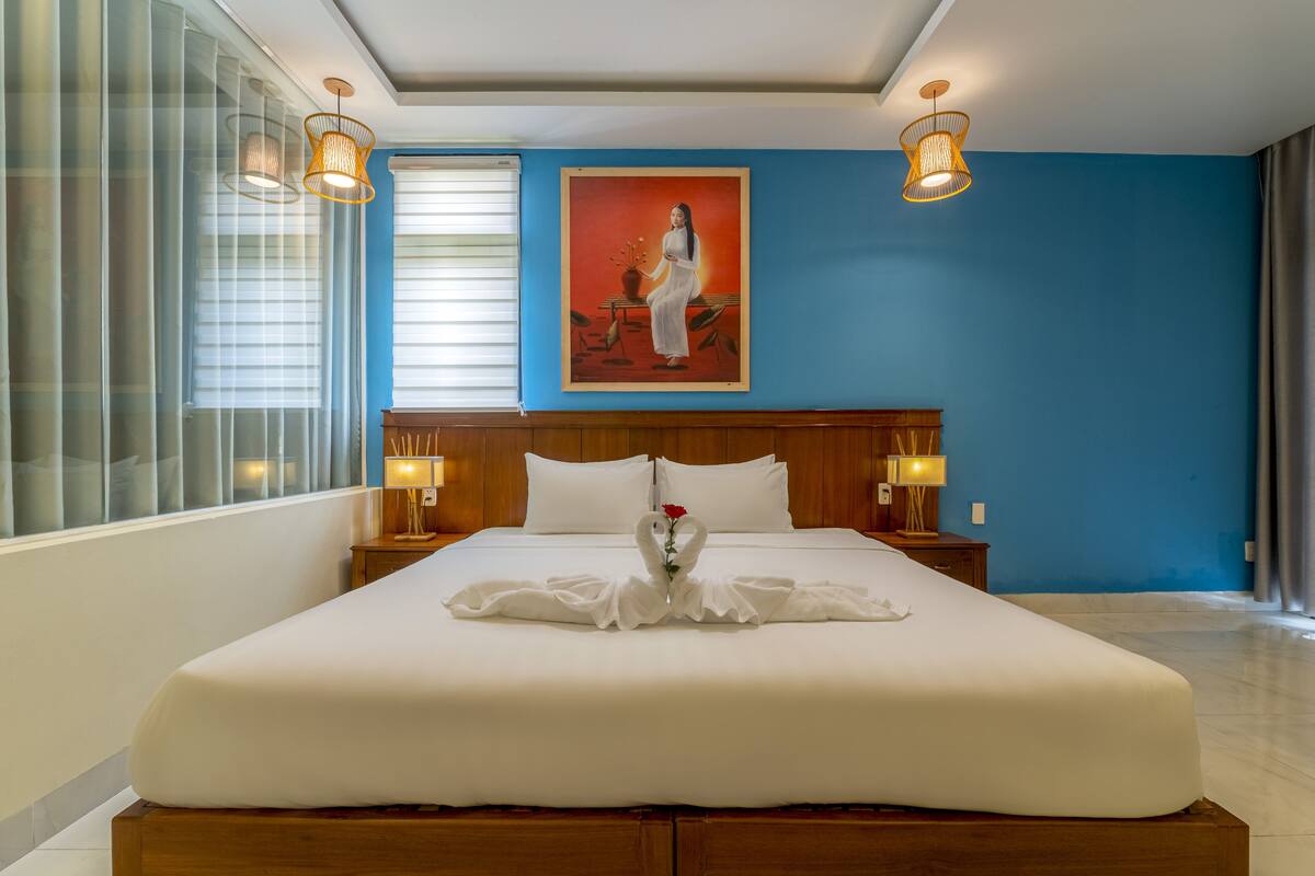 Ein Hotelzimmer mit einem großen Bett, einem Bild an der Wand und zwei Nachttischlampen.