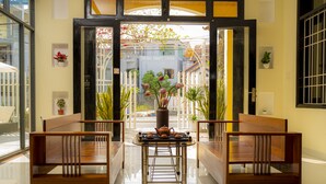 Um saguão moderno de hotel com uma mesa central, dois bancos de madeira e vista para a rua.