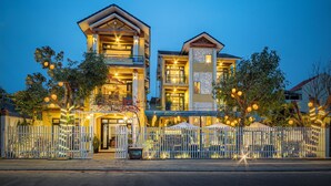Hotel de dois andares com cerca branca, área de estar externa e luzes de Natal.
