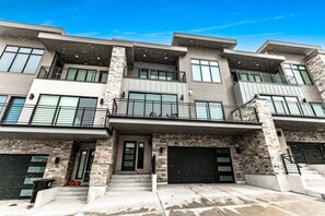 A multi-story residential building with a modern architectural style, featuring balconies, large windows, and a garage.