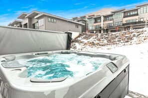 A hot tub in a snowy outdoor setting with modern buildings in the background.