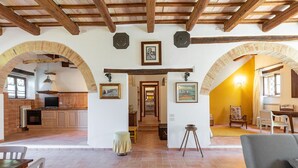 Amplia sala de estar con vigas de madera a la vista, cocina con armarios de madera y comedor con mesa y sillas.
