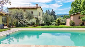 Una piscina rectangular con borde de azulejos, rodeada por una zona pavimentada.
