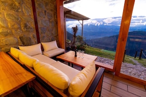 Relax in a serene outdoor space with a stone wall backdrop, overlooking breathtaking mountain and valley views.