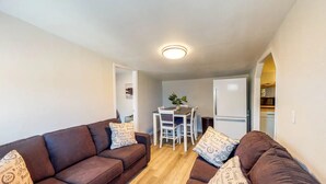 Un espace de vie compact comprenant un canapé marron, une table à manger avec des chaises et un réfrigérateur blanc.