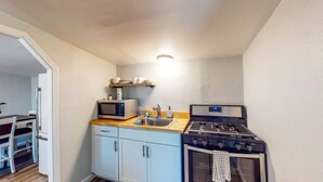 Une cuisine compacte équipée d’un four à micro-ondes, d’un évier et d’une cuisinière à gaz.