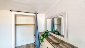 Une salle de bain avec un rideau de douche, un miroir, un meuble-lavabo en bois et une plante en pot.